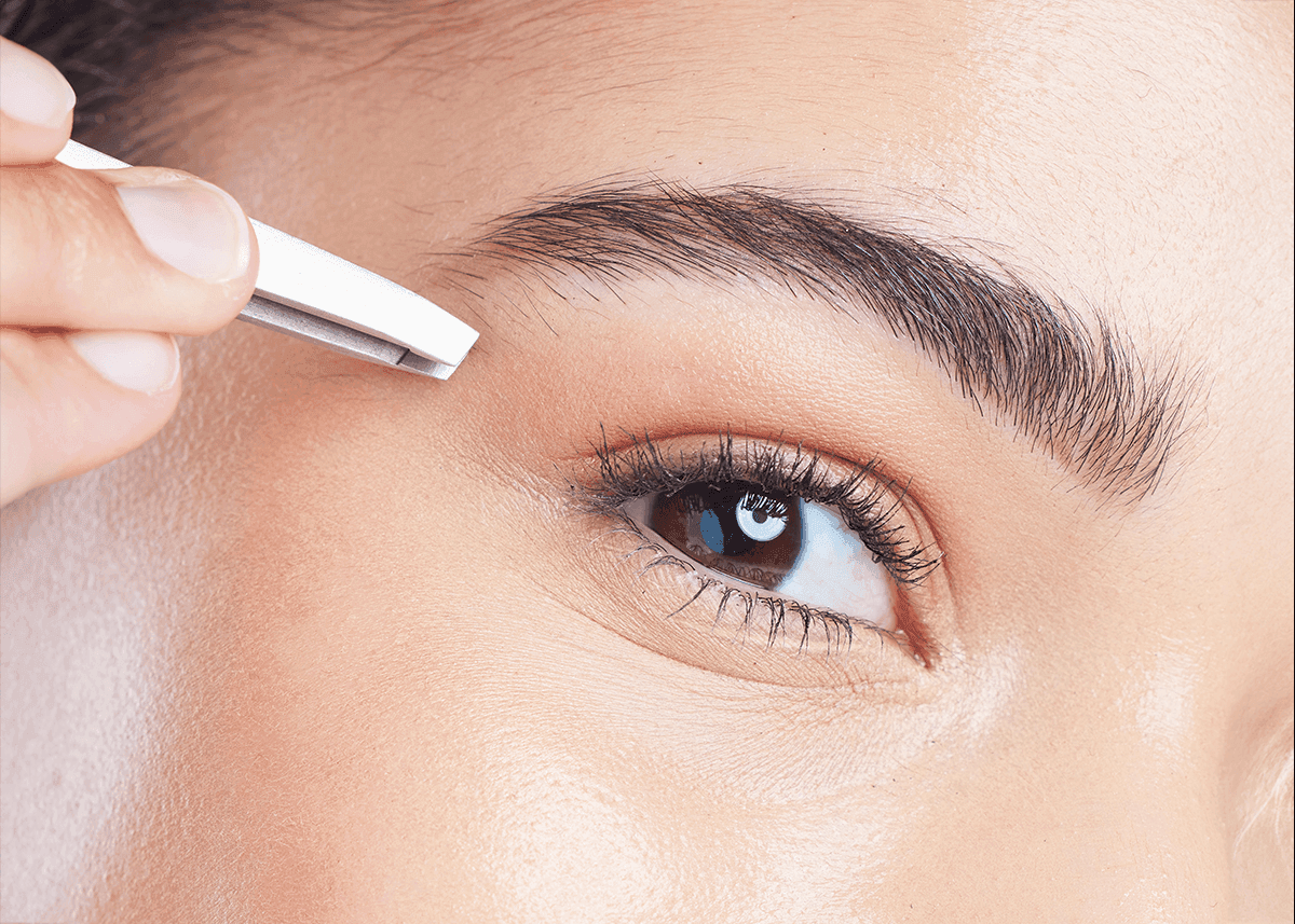 girl plucking eyebrows with tweezer