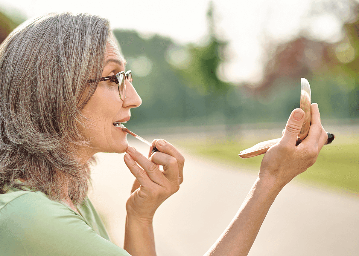 Profile of woman applying lipstick