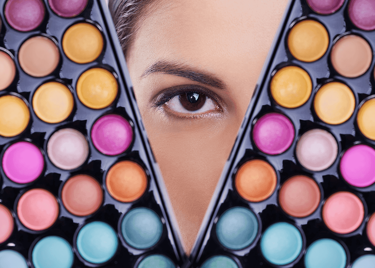 woman posing behind eyeshadow palettes